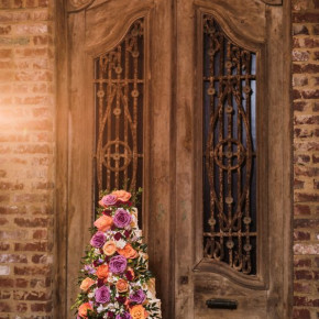 Wedding cake with floral in purple, orange, and greenery.   Photo by Snap Happy Floral and décor by Southern Event Planners