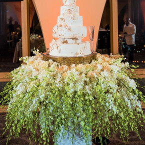Stunning white and gold cake with cake table covered in white and green floral on pedestal. New Year's Eve Wedding   Floral and Decor by Southern Event Planners  Photo by SkyTouch_E_Photos